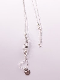 Flutter is a Crystal Essence Necklace; clear crystal stones, sterling silver beads, two sterling silver heart charms.