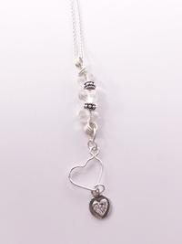 Flutter is a Crystal Essence Necklace; clear crystal stones, sterling silver beads, two sterling silver heart charms.